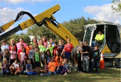 Kids posing with heavy equipment and smiling